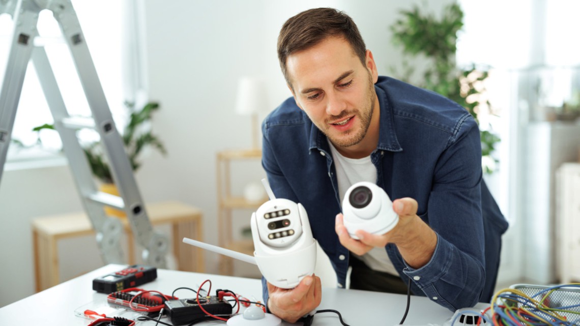 Young electrician installing security cameras at home